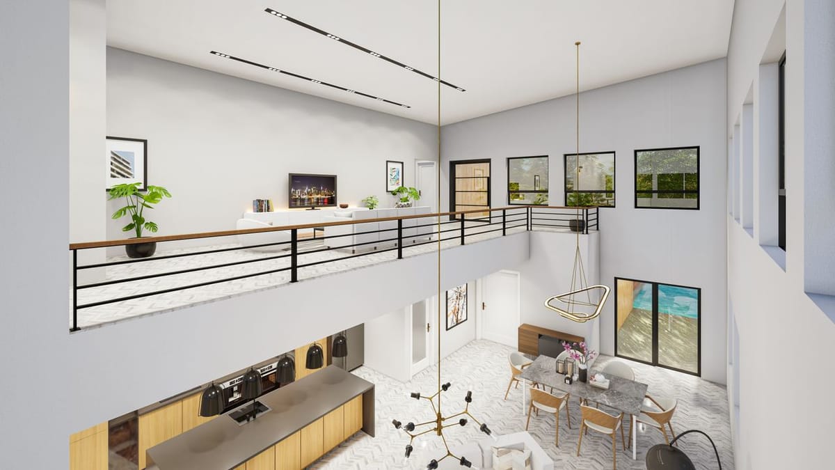 A double-height open-plan interior with a mezzanine level, pendant chandelier, kitchen island, and dining table below.
